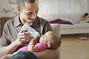 Man feeding baby with bottle.